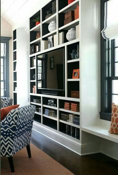 a living room filled with furniture and a flat screen tv on top of a book shelf