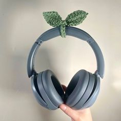 a pair of headphones with leaves attached to the headset, held up against a wall