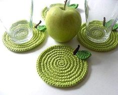 three green coasters and an apple on a white table top with two glasses in the middle