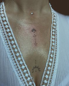 a close up of a woman's chest with a cross tattoo on her chest