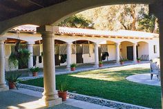 an outdoor courtyard with chairs and potted plants on the lawn in front of it