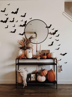 a table with pumpkins and bats on it in front of a wall mounted mirror