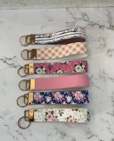 four key fobs are lined up on a marble counter with flowers and gingham