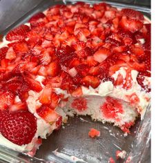 a cake with strawberries on top is cut into pieces and sits in a pan