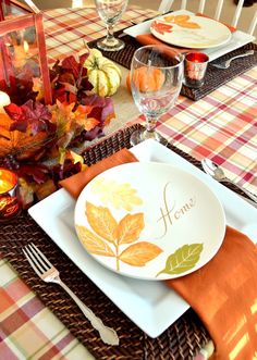 the table is set for thanksgiving dinner with plates and silverware, napkins and candles