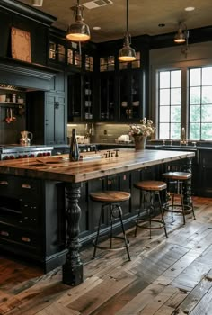 a large kitchen with wooden floors and black cabinets, an island in the middle is surrounded by stools