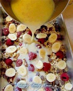 a bowl filled with granola, fruit and yogurt next to a glass of orange juice