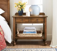 a wooden table with a basket on top of it next to a bed and window