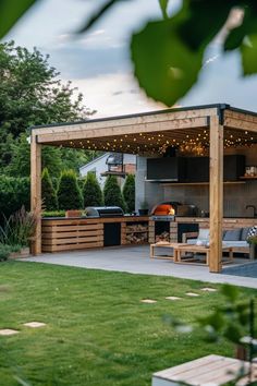 an outdoor kitchen is built into the side of a house with lights strung up on it