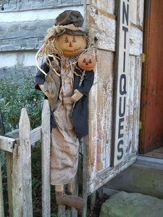 an old scarecrow doll hanging on a wooden fence