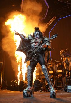 an image of a man that is on stage with fire in the air behind him