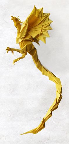 a yellow origami dragon sitting on top of a white surface