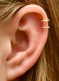 a woman's ear is shown with three thin gold rings