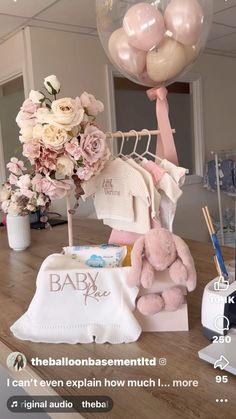 a baby shower with balloons, diaper and teddy bear on the table next to it