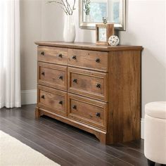 a wooden dresser sitting in front of a mirror on top of a hard wood floor