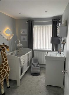 a giraffe standing next to a baby crib in a room with grey walls