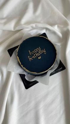 a birthday cake sitting on top of a white cloth covered tablecloth with the words happy birthday written on it