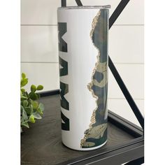 a white and black vase sitting on top of a table next to a potted plant