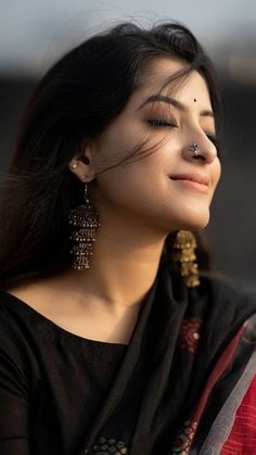 a woman with her eyes closed wearing earrings