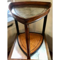 a wooden table with marble top and leather trim around the edges, on display in a room