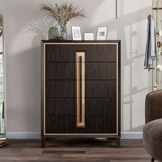 a brown cabinet with gold handles and drawers in a room next to a chair, mirror and potted plant