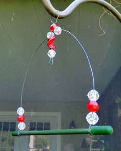 a wind chime hanging from a tree branch with red and white beads on it