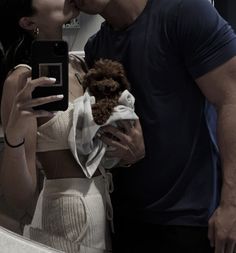 a man and woman kissing in front of a mirror while holding a teddy bear,