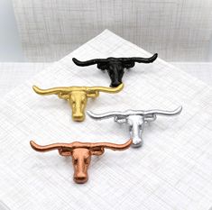 three metal bull heads sitting on top of a white cloth