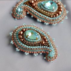 two pairs of beaded earrings with blue and brown beads on the sides, one is shaped like a peacock