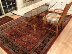 a glass table with chairs and rug on the floor