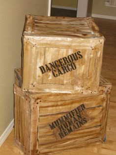 two wooden boxes sitting on top of a hard wood floor next to a wall with the words dangerous cargo written on them