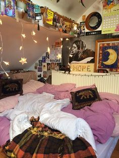 an unmade bed in a dorm room with lights strung from the ceiling and pictures on the wall