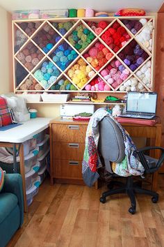 a room with a chair, desk and shelves filled with yarn