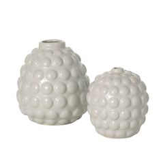 two white vases sitting next to each other on a white surface with circles in the middle