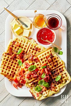 waffles with bacon, tomatoes and cheese on a white plate next to condiments