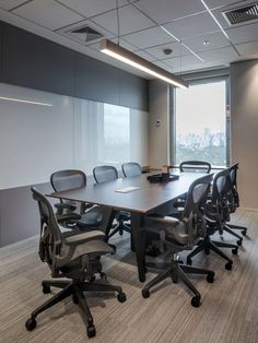 an empty conference room with chairs and a large table in front of a window overlooking the city