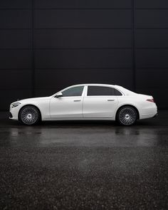 a white car is parked in front of a black wall and it's shiny chrome rims