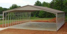 a metal carport sitting in the middle of a dirt field next to some trees