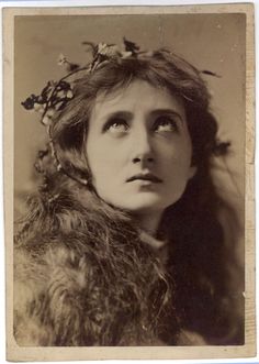 an old black and white photo of a woman wearing a fur coat with flowers in her hair