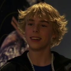 a young boy with blonde hair wearing a black jacket