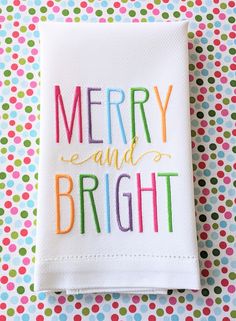 a white dish towel with the words merry and bright written in multicolored letters