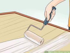 a person using a paint roller on the floor with a wooden plank in front of them