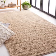 a large rug is shown with a plant in the corner and a pillow on the floor next to it