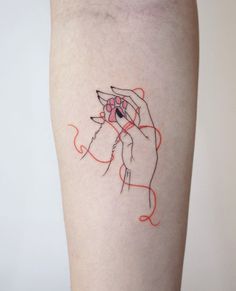 a woman's arm with a tattoo on it that has an image of a hand holding a yarn ball