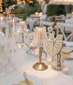 the table is set with white linens and gold chargers, candles, and glassware