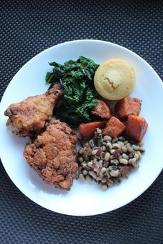 a white plate topped with meat, beans and greens