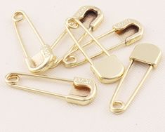 gold plated metal safety pins on white background