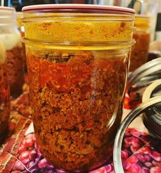 several jars filled with food sitting on top of a colorful table cloth next to utensils