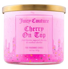 a pink candle with sprinkles and gold rimmed lid that says juicy confection cherry on top