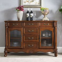 a wooden sideboard with wine glasses and bottles on it in front of a painting